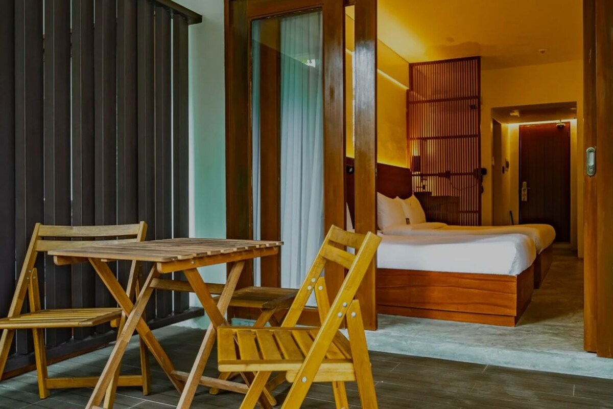 A hotel room with a bed, a wooden table, and chairs.