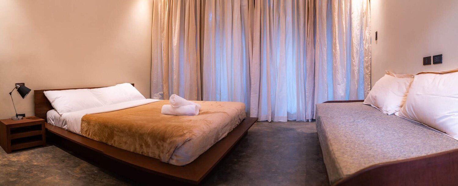 A hotel room with a bed, a bedside table, and a sofa.