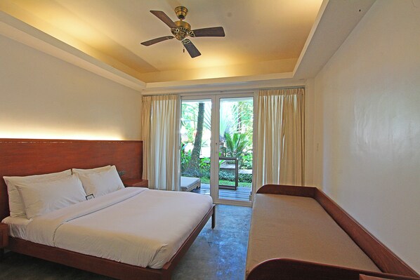 A hotel room with a bed, a smaller bed, a ceiling fan, and a view of greenery through the window. - The Henry Resort at Kermit Siargao (General Luna)