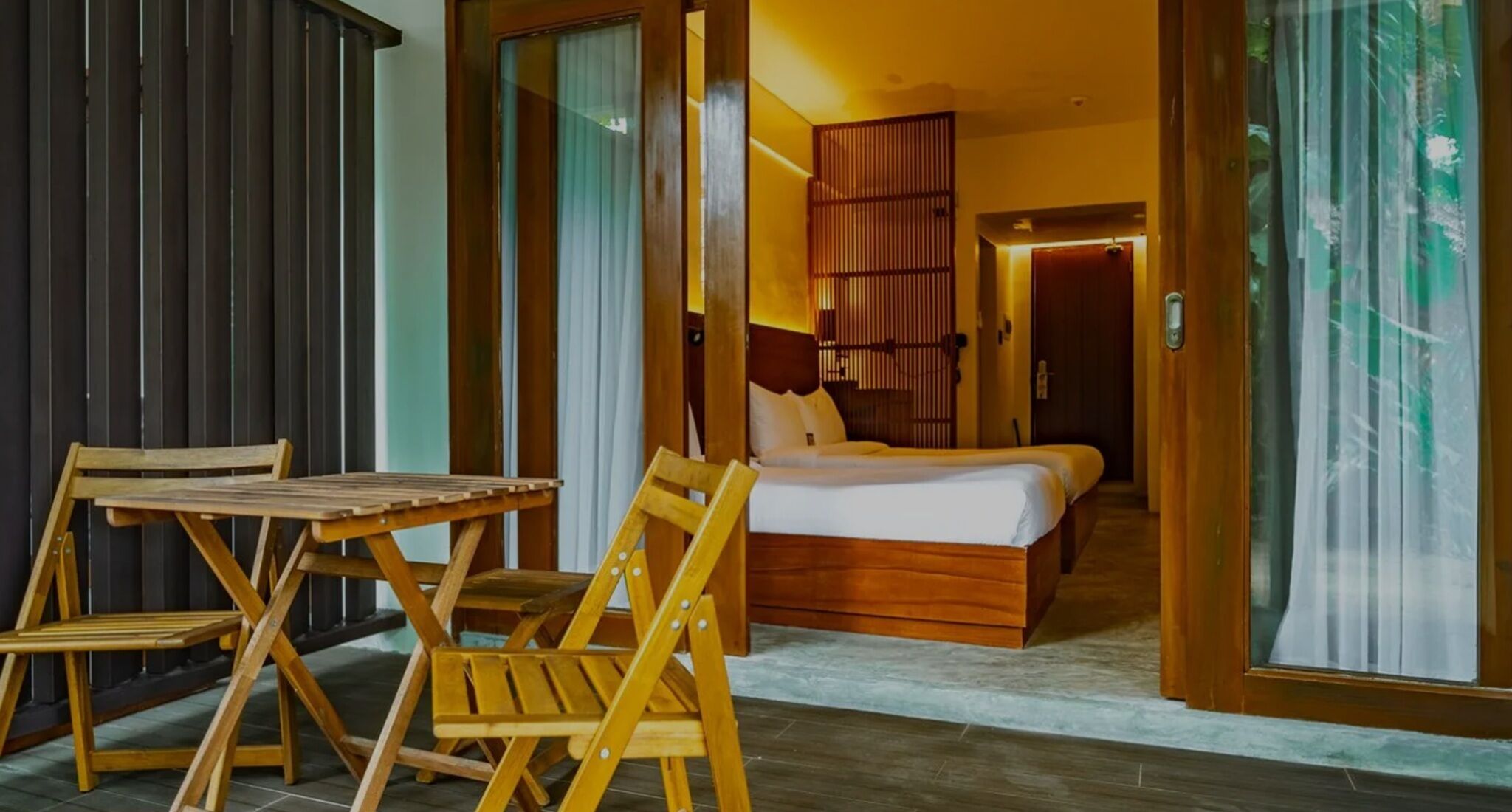 Una habitación de hotel con una cama, una mesa de madera y sillas.