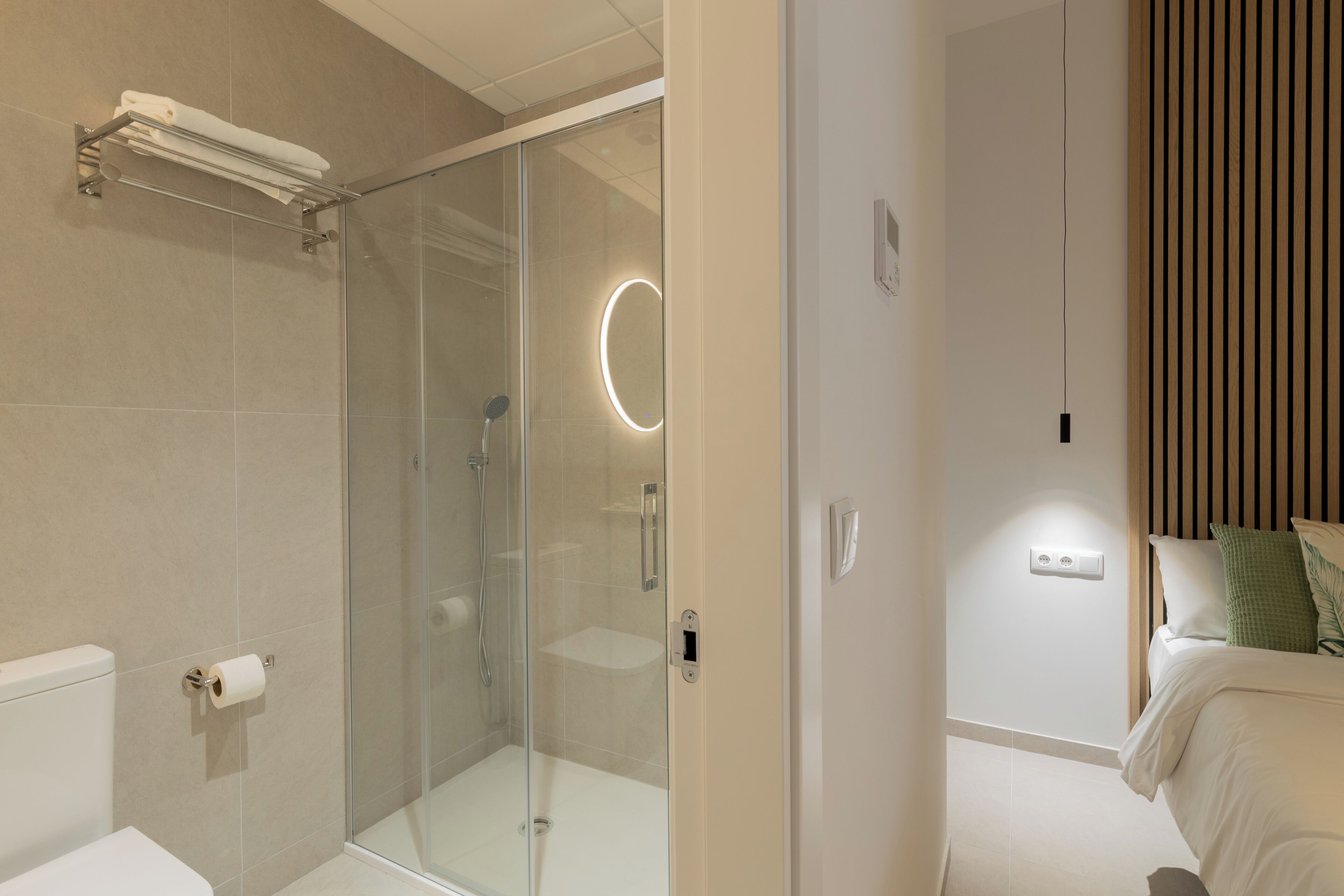 A modern bathroom with a glass-enclosed shower, a toilet, and a towel rack.