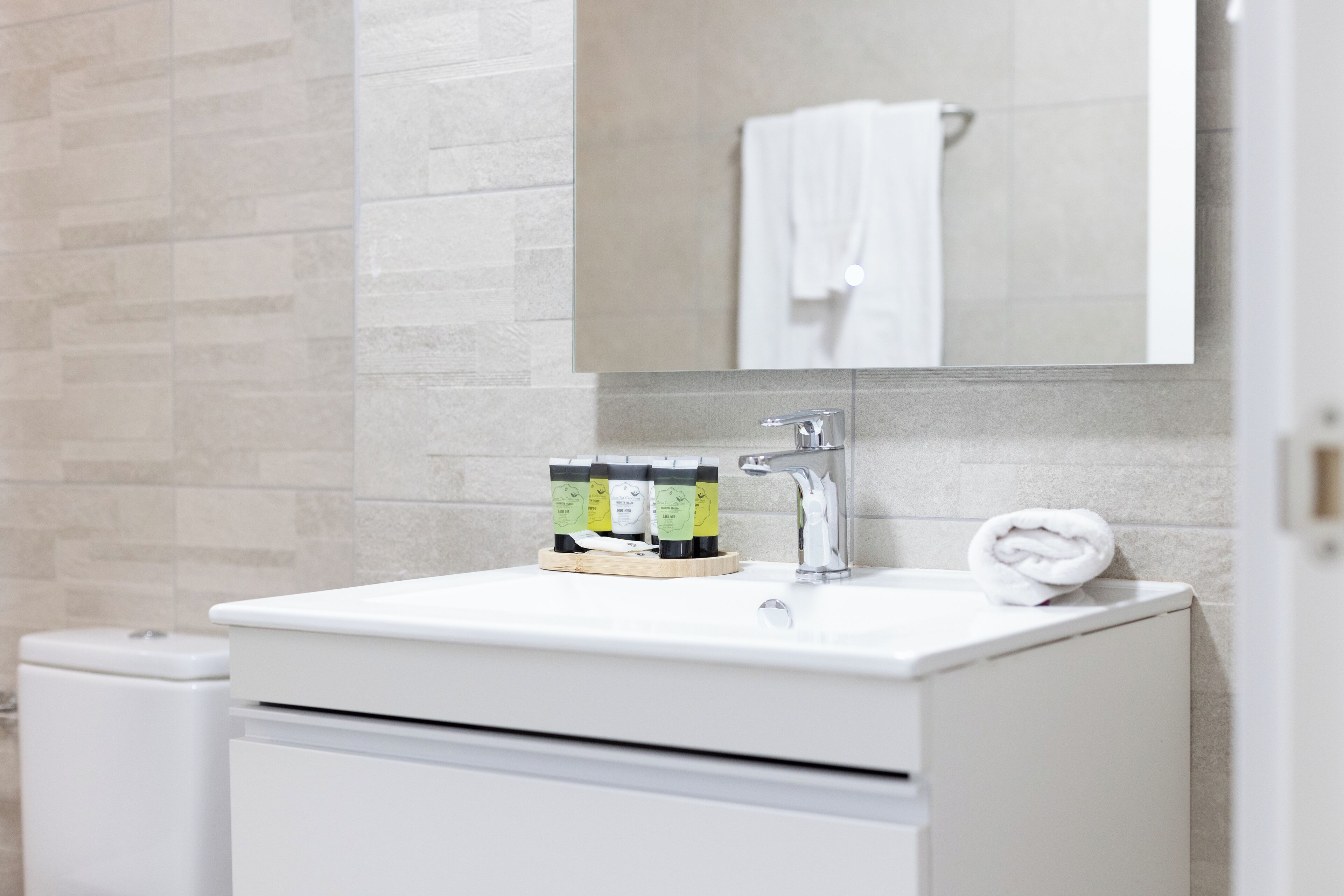 Un bagno moderno con un lavandino bianco, uno specchio sopra e un asciugamano sul ripiano.