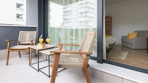 Ein Balkon mit zwei Holzstühlen, einem kleinen Tisch und einer Glastrennwand.