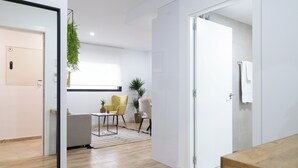Ein modernes Hotelzimmer mit Holzboden, einer Couch, einem Esstisch und einer kleinen Küchenzeile.