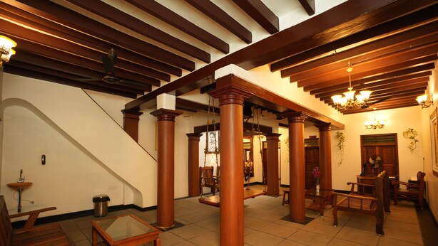 A spacious lobby with wooden columns, a staircase, and a chandelier. - Rebel De Pondicherry (Puducherry)