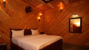 A cozy, wooden-paneled bedroom with a bed, bedside lamps, and a mirror on the wall. - Rebel De Pondicherry (Puducherry)