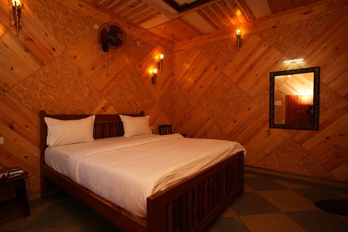 A cozy, wooden-paneled bedroom with a bed, bedside lamps, and a mirror on the wall.