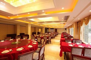 Un salón de banquetes con mesas redondas, sillas y una araña.