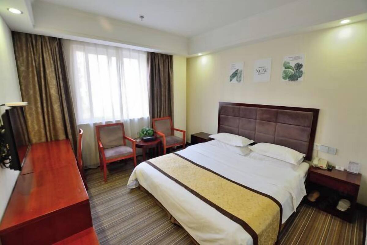Une chambre d’hôtel avec un lit, un bureau, une chaise et une petite table sur laquelle se trouve une plante.