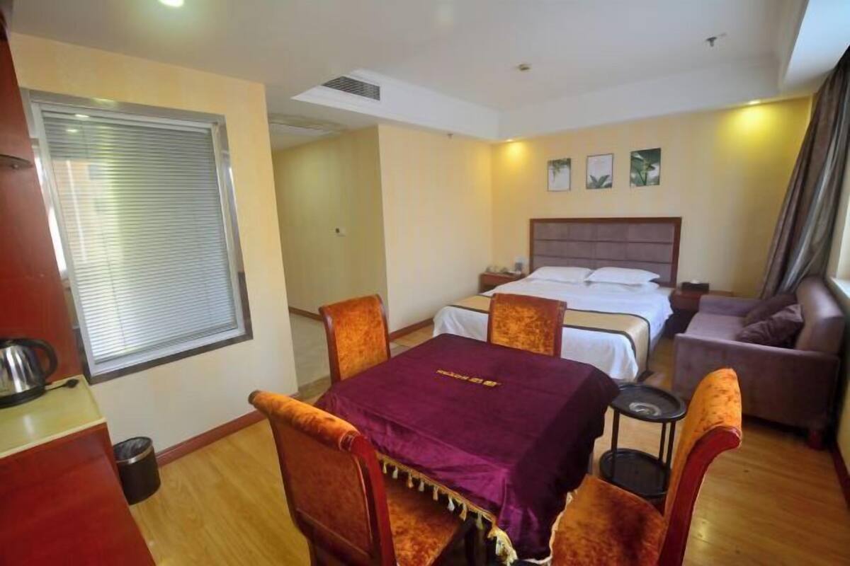 Une chambre d’hôtel comprenant un lit, un canapé, une table à manger avec des chaises et une petite table avec une lampe.