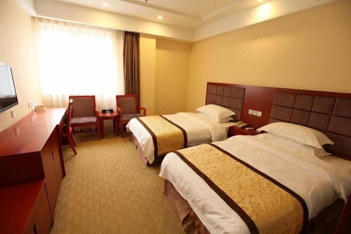 Une chambre d’hôtel avec deux lits, un bureau, une chaise et un téléviseur.