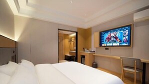 A hotel room with a large bed, a desk, a chair, a television, and a bathroom visible through an open door. - Huangguan Holiday Hotel (Liyang)