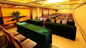 A conference room with rows of tables and chairs, a large painting on the wall, and a potted plant. - Huangguan Holiday Hotel (Liyang)