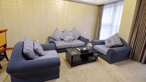 A living room with two sofas, a coffee table, and a wooden side table. - Huangguan Holiday Hotel (Liyang)