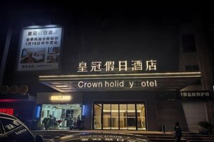 Entrada de un hotel con señalización iluminada, acceso visible y una persona parada afuera.