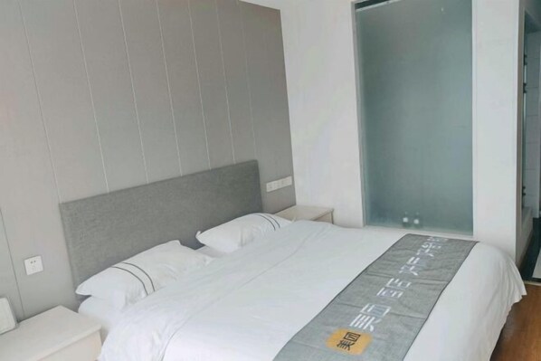Una habitación de hotel moderna con una cama grande, cabecera gris y mesita de noche.