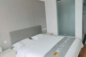 Una habitación de hotel moderna con una cama grande, cabecera gris y mesita de noche.