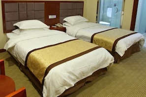Habitación de hotel con dos camas, cada una con cabecera, mesitas de noche y teléfono.