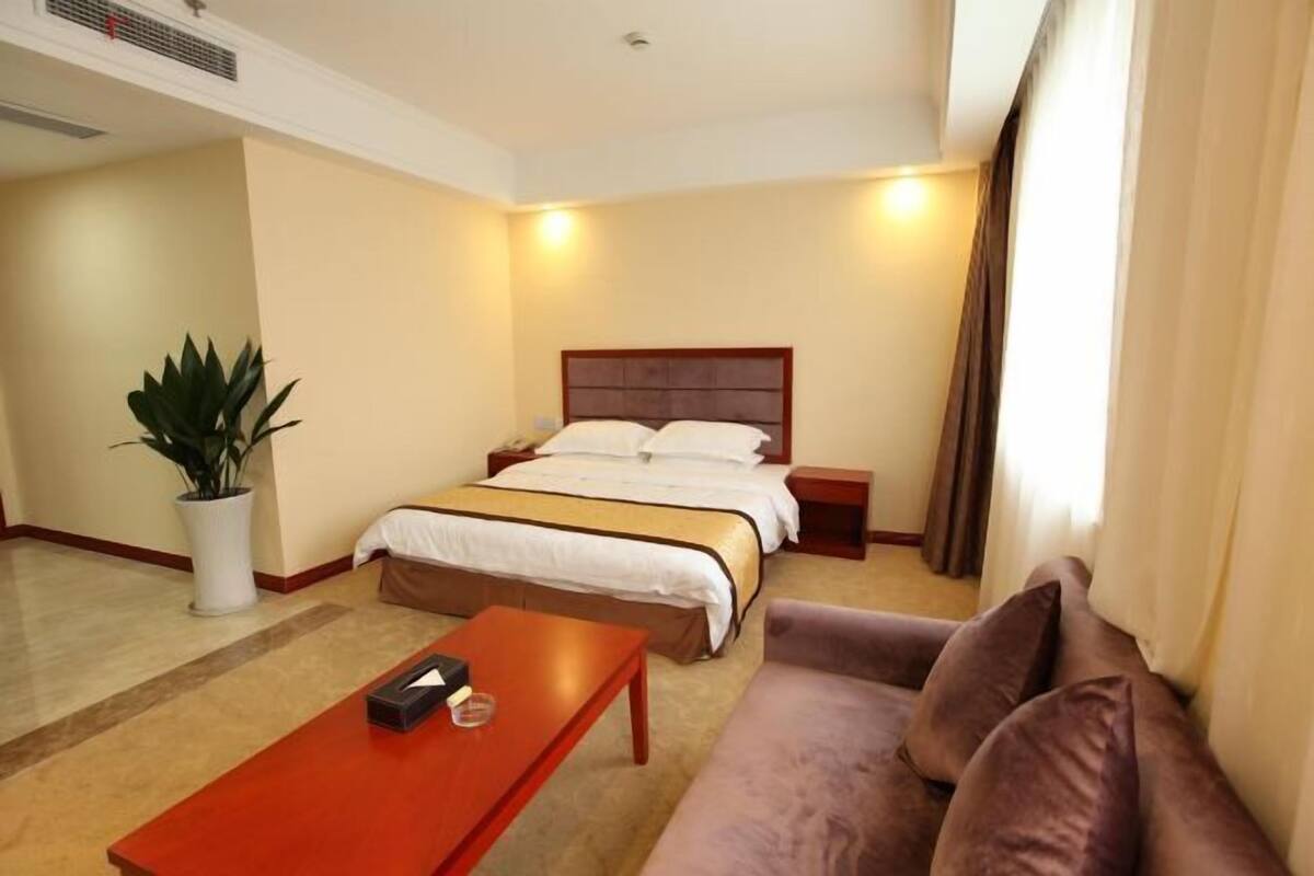 Une chambre d’hôtel comprenant un lit, une table de chevet, une table basse, un canapé et une plante en pot.
