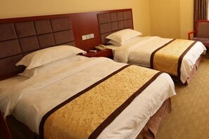A hotel room with two beds, each with a headboard, a bedside table with a phone, and a carpeted floor. - Huangguan Holiday Hotel (Liyang)