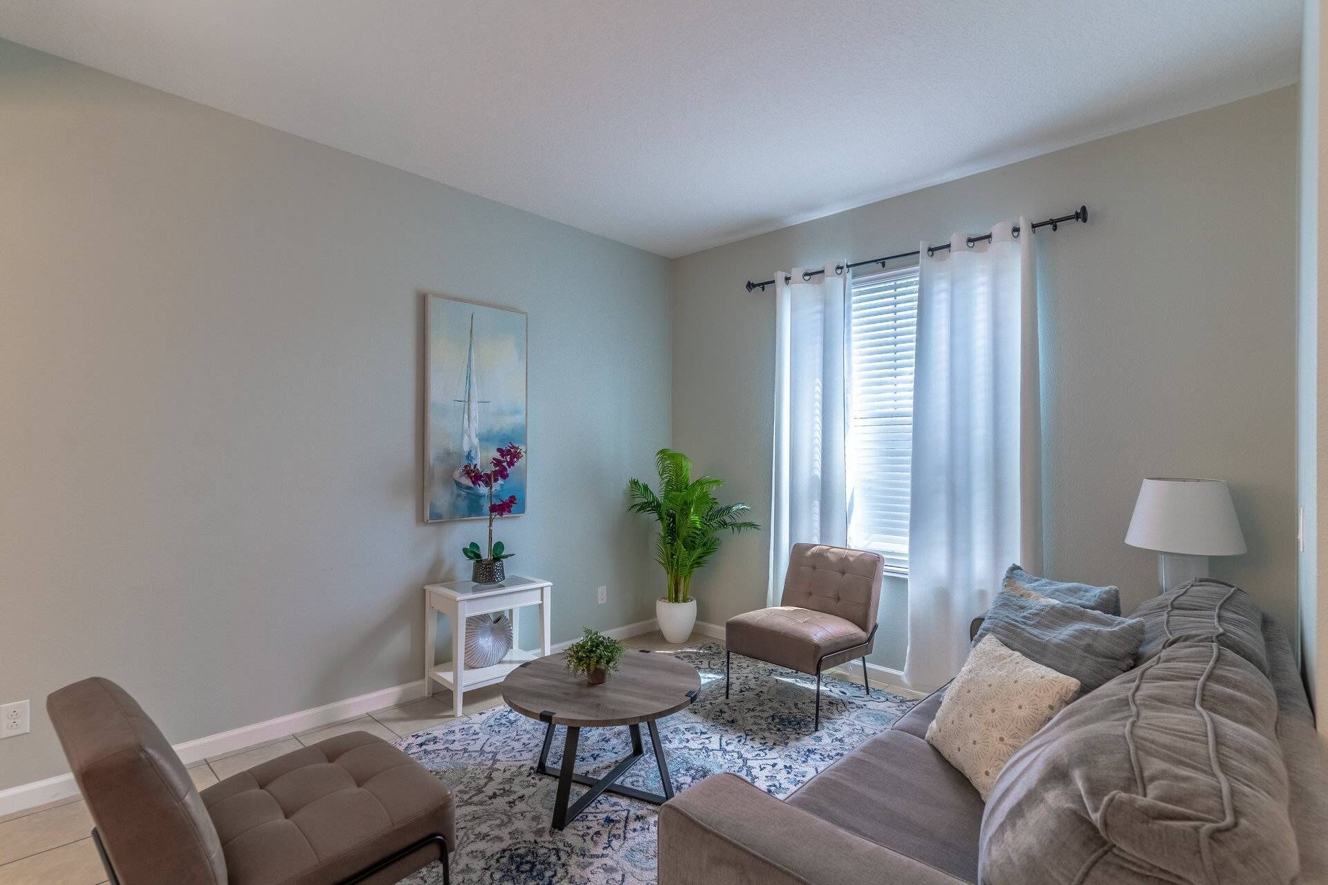 Uma sala de estar com sofá, poltrona, mesa de centro e um quadro na parede.