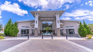 A modern building with a central entrance, surrounded by landscaped areas and trees.