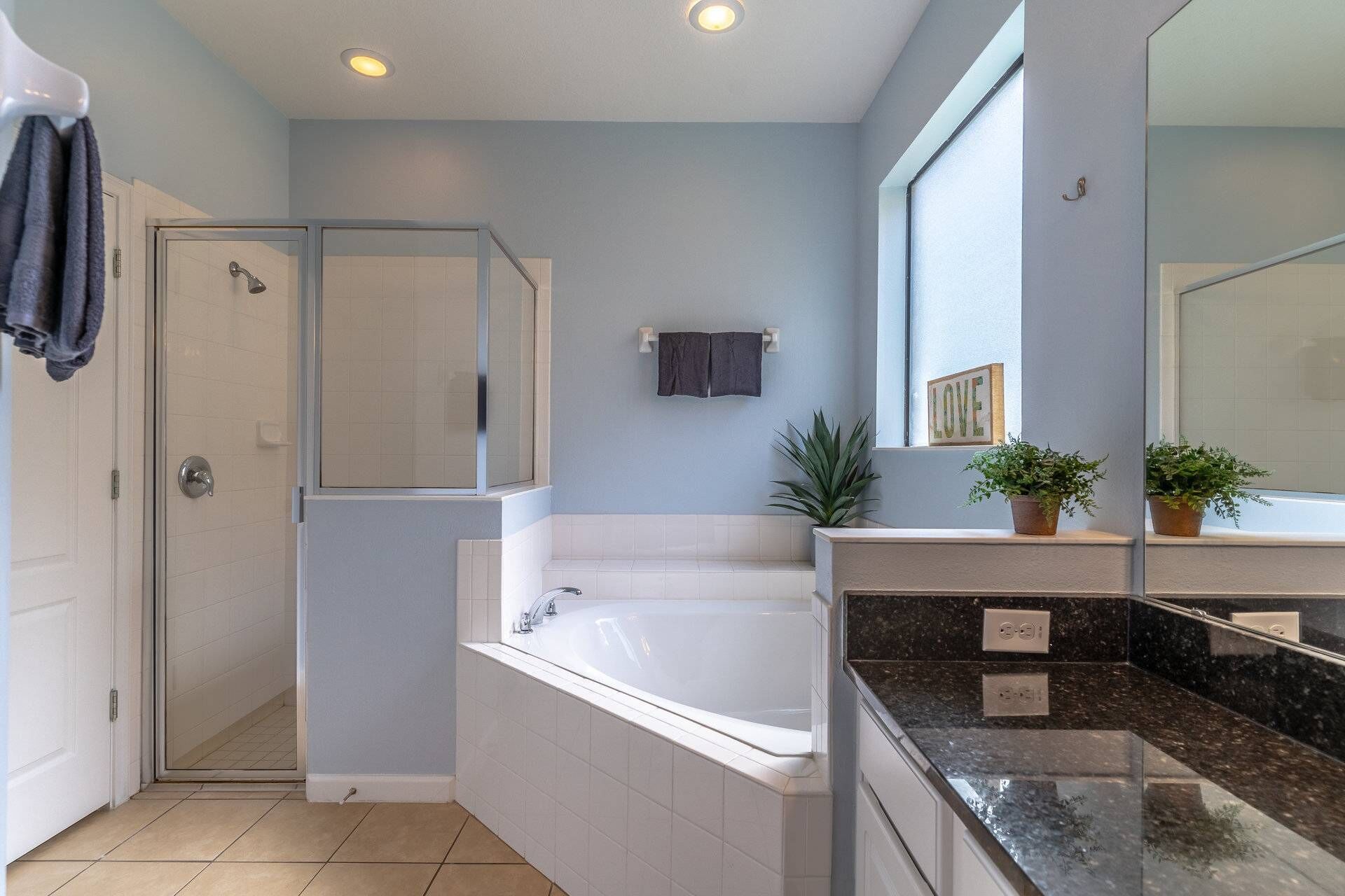 A modern bathroom with a glass shower enclosure, a freestanding bathtub, and a vanity with a large mirror.