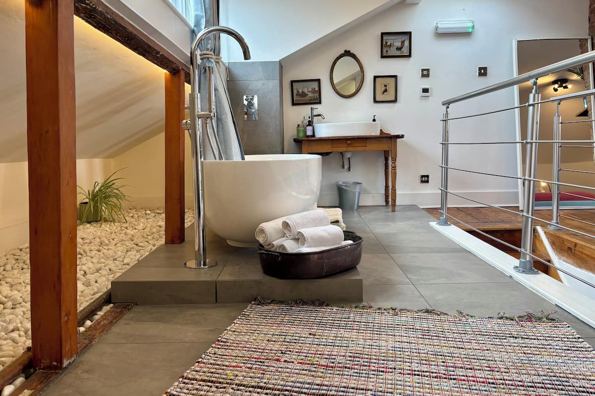 A modern bathroom with a freestanding bathtub, a large mirror, and a sink with toiletries.