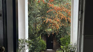 A doorway leading to a garden with a pathway, potted plants, and a brick wall. - Central Victorian House (London)