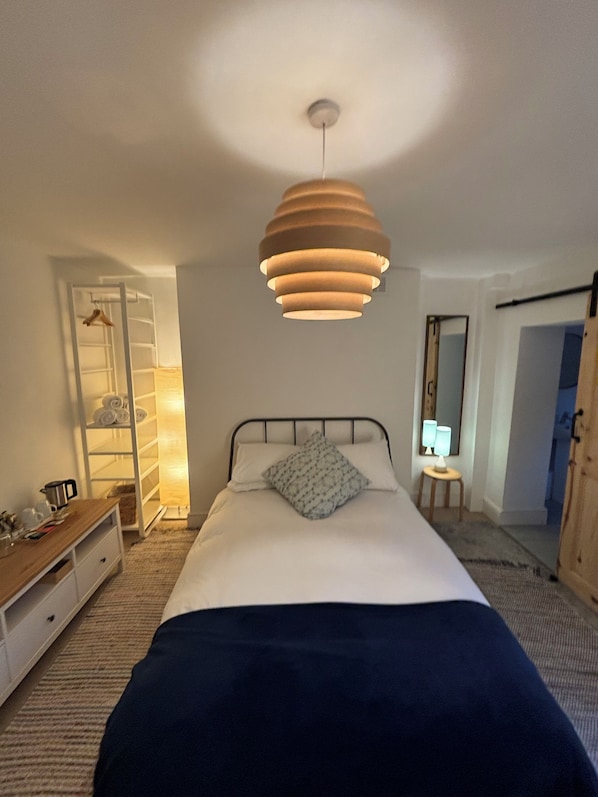 A bedroom with a bed, bedside table, hanging light fixture, wardrobe, and a mirror. - Central Victorian House (London)