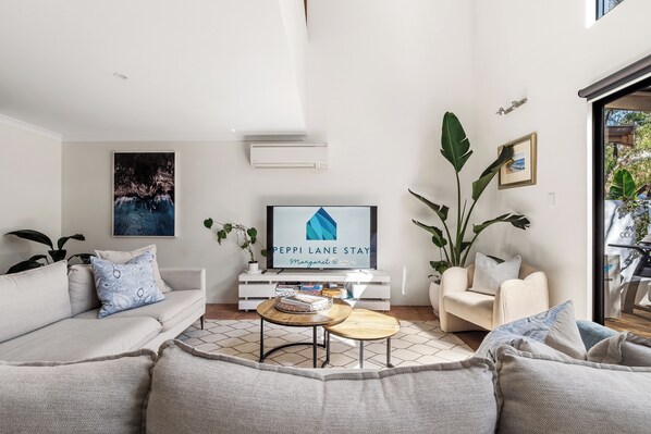 Una sala de estar moderna con un sofá, una mesa de centro y un televisor de pantalla plana.