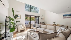Una sala moderna con un sofá, sillones, una mesa de centro y plantas en macetas.
