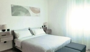 A bedroom with a bed, bedside tables, a nightstand, a lamp, and a window with curtains. - CASA MAFALDA Near the train station - historic center - private on-site parking (Imola)