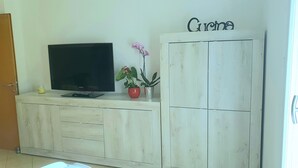 A wooden entertainment center with a flat-screen TV, a small plant, and a decorative sign. - CASA MAFALDA Station area - historic center - theater with indoor parking. (Imola)