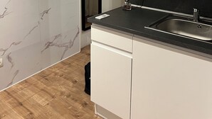 Una cocina moderna con armarios blancos, una encimera negra, un microondas y un fregadero.