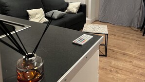 Una sala de estar moderna con un sofá negro, una mesita de centro pequeña y un candelabro de vidrio.