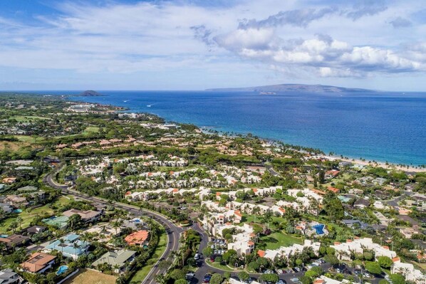 An aerial view of a coastal residential area with houses, roads, and a beach.