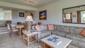 Ein Wohnzimmer mit einer Couch, einem Couchtisch, einem Esstisch mit Stühlen, einer Lampe und einem großen Spiegel.