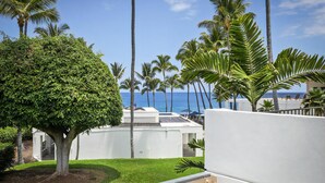 A resort with a pool area, palm trees, and a view of the ocean. - Royal Sea Cliff Kona 202 Ocean View 1 Bedroom (Kailua Kona)