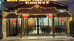 Un ristorante chiamato Van Anh Restaurant con uno stile architettonico tradizionale, caratterizzato da un tetto in tegole e luci decorative illuminate.