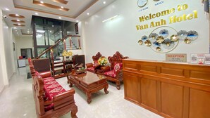 Un'area di accoglienza con una reception, una scala e un pannello che espone orologi e un cartello di benvenuto per l'Hotel Van Anh.