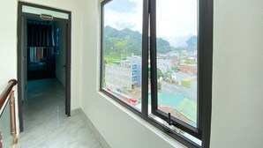 Una camera d'hotel con un'ampia finestra che si affaccia su un paesaggio montuoso e sulla città.