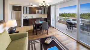 A modern hotel room with a kitchen, dining area, and balcony with a view. - Regency on Beachwalk City View 1 Bedroom (Honolulu)