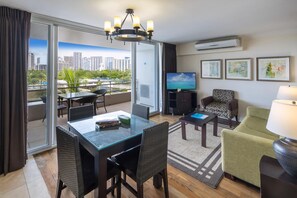 Quarto de hotel moderno com varanda, área de refeições, televisão e obras de arte nas paredes.