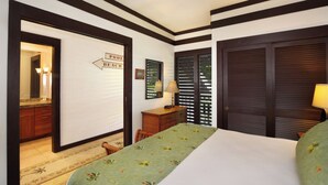 Ein Hotelzimmer mit Bett, Schminktisch, Spiegel, einem Schild mit Pool- und Strandhinweis sowie einem Fenster mit Jalousien.