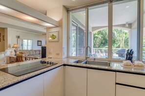 A modern kitchen with a large window, granite countertops, and a built-in stove.