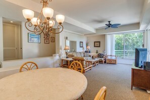 A spacious living area with a dining table, sofas, and a television.