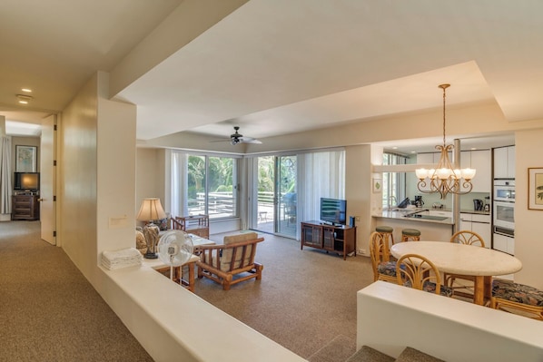 A spacious living area with a balcony, a dining set, and a kitchen area.