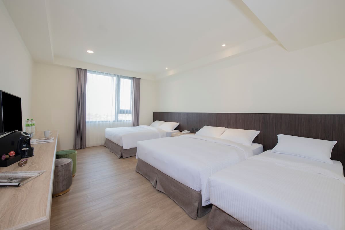Quarto de hotel com duas camas, uma mesa com cafeteira e televisão.