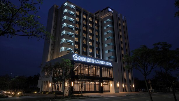 A modern hotel building with illuminated signage, multiple floors, and a prominent entrance. - FLORAMOS HOTEL   (Tianzhong)